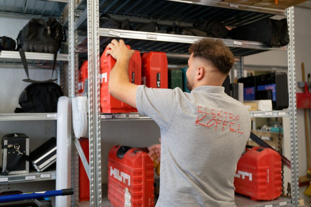 Mitarbeiter von Elektro Köffel beim Einräumen von Werkzeugkoffern im Lager – Einsatzvorbereitung im Elektrohandwerk