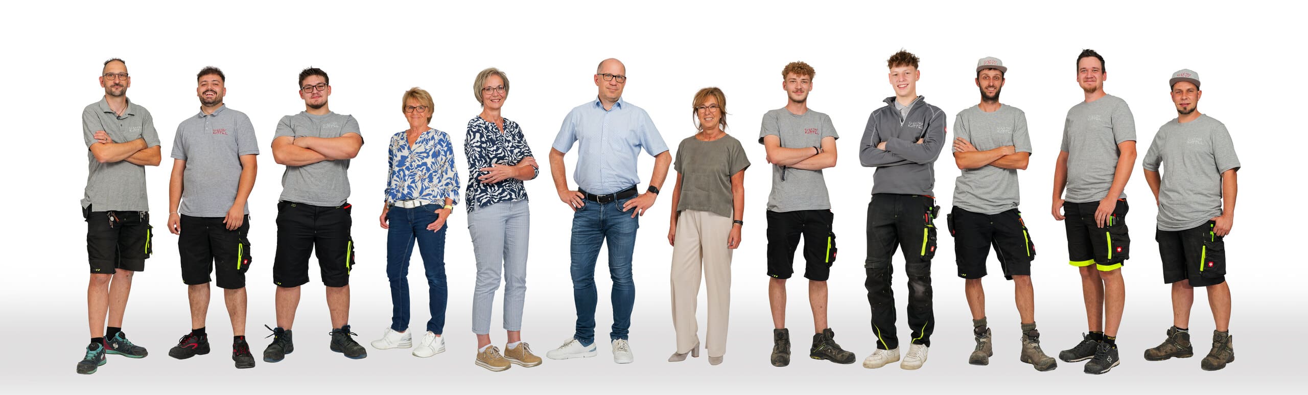 Das Team der Alfred Köffel GmbH – Elektriker:innen, Lehrlinge und Bürokräfte vor weißem Hintergrund